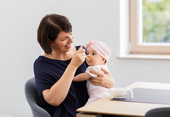 Image showing middle-aged mother feeding baby daughter at home