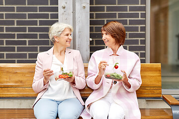 Image showing senior women eating takeaway food on city street