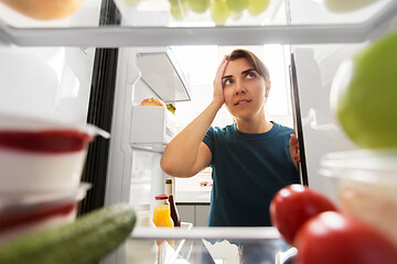 Image showing crazy woman at open fridge holding to head