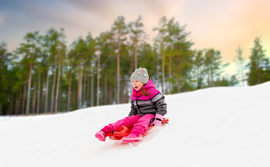 Image showing happy little girl sliding down on sled in winter