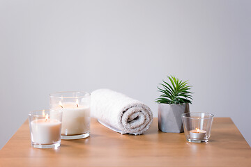 Image showing burning fragrance candles and bath towel on table