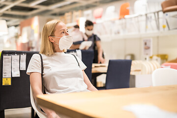 Image showing New normal during covid epidemic. Caucasian woman shopping at retail furniture and home accessories store wearing protective medical face mask to prevent spreading of corona virus