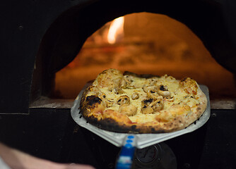 Image showing chef removing hot pizza from stove