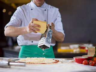 Image showing chef sprinkling cheese over fresh pizza dough