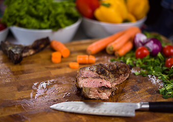 Image showing Juicy slices of grilled steak on wooden board