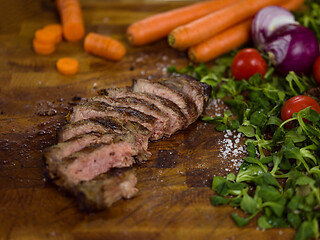 Image showing Juicy slices of grilled steak on wooden board