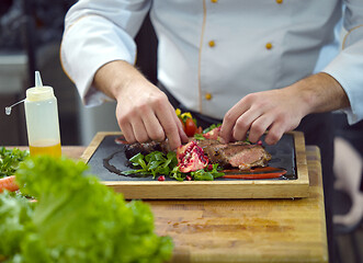 Image showing closeup of Chef hands serving beef steak