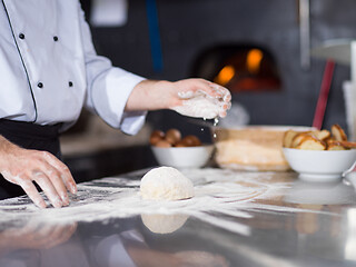 Image showing chef sprinkling flour over fresh pizza dough