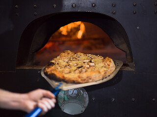 Image showing chef removing hot pizza from stove