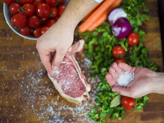 Image showing Chef putting salt on juicy slice of raw steak