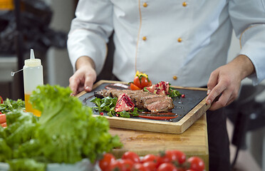 Image showing closeup of Chef hands serving beef steak