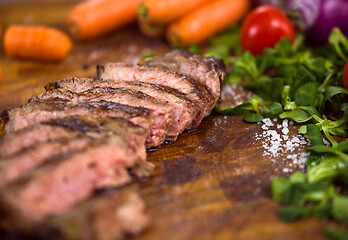 Image showing Juicy slices of grilled steak on wooden board