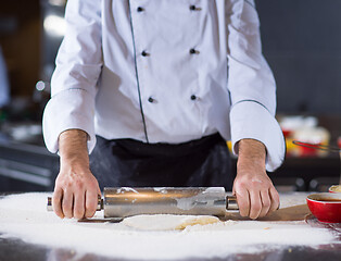 Image showing chef preparing dough for pizza with rolling pin