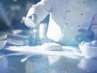 Image showing chef sprinkling flour over fresh pizza dough
