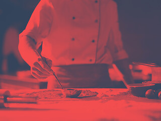 Image showing Chef smearing pizza dough with ketchup