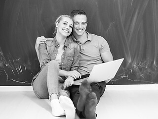 Image showing couple using laptop in front of gray chalkboard