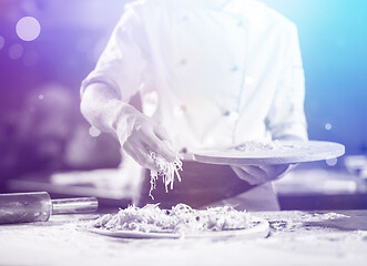 Image showing chef sprinkling cheese over fresh pizza dough