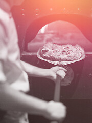 Image showing chef removing hot pizza from stove