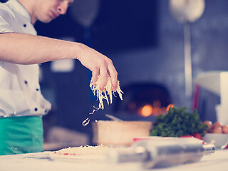 Image showing chef sprinkling cheese over fresh pizza dough