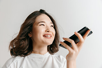 Image showing Indoor portrait of attractive young asian woman holding blank smartphone