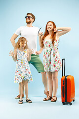 Image showing Happy parent with daughter and suitcase at studio isolated on blue background