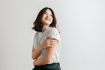 Image showing Happy asian woman standing and smiling against gray background.