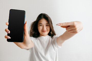 Image showing Portrait of a confident casual asian girl showing blank screen of mobile phone