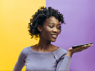 Image showing Indoor portrait of attractive young black woman holding blank smartphone