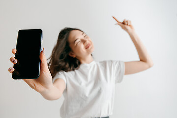 Image showing Portrait of a confident casual asian girl showing blank screen of mobile phone