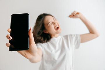 Image showing Portrait of a confident casual asian girl showing blank screen of mobile phone