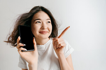 Image showing Portrait of a confident casual asian girl showing blank screen of mobile phone