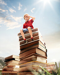 Image showing Little boy sitting on the tower made of big books