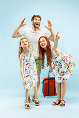 Image showing Happy parent with daughter and suitcase at studio isolated on blue background