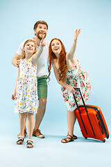 Image showing Happy parent with daughter and suitcase at studio isolated on blue background