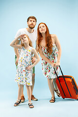 Image showing Happy parent with daughter and suitcase at studio isolated on blue background