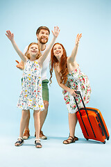 Image showing Happy parent with daughter and suitcase at studio isolated on blue background