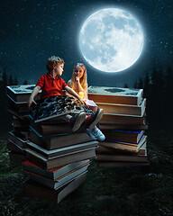 Image showing Little girl and boy sitting on the tower made of big books