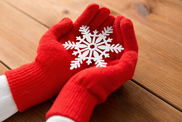 Image showing hands in red woollen gloves holding big snowflake