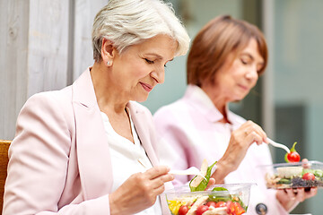 Image showing senior women eating takeaway food on city street