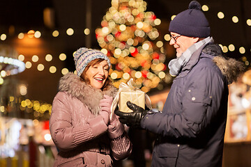 Image showing happy senior couple with gift at christmas market