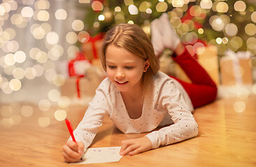 Image showing smiling girl writing christmas wish list at home