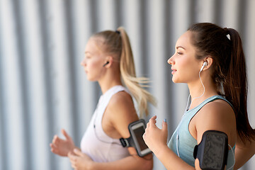 Image showing young women with earphones and smartphones running