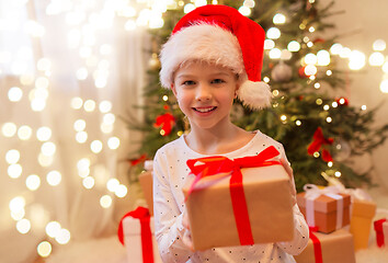 Image showing smiling girl in santa hat with christmas gift
