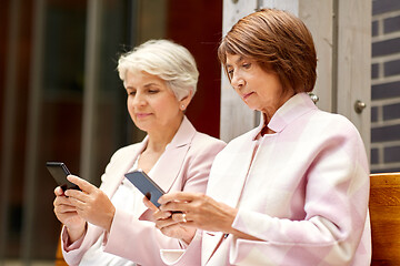 Image showing happy senior women with smartphones in city