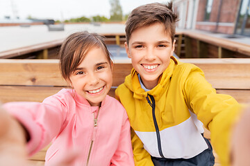 Image showing children sitting on street bench and taking selfie