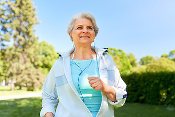 Image showing senior woman with earphones running in summer park