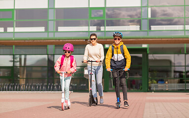 Image showing happy school children with mother riding scooters