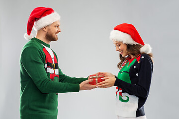 Image showing happy couple in christmas sweaters with gift box