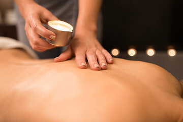 Image showing back massage with hot oil candle at spa