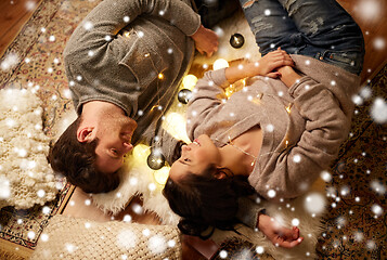 Image showing happy couple with garland lying on floor at home